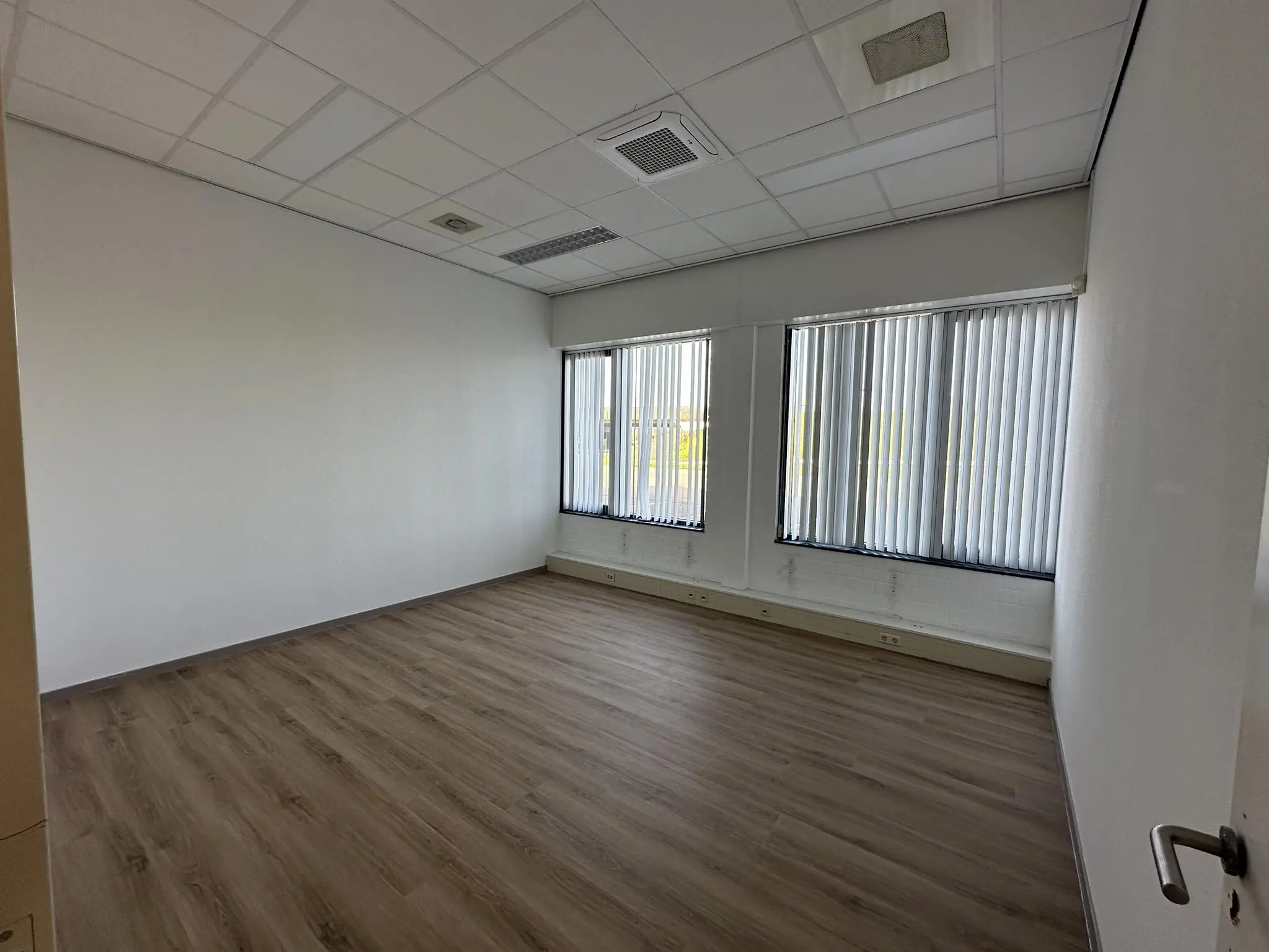 Leeg kantoorruimte met laminaatvloer en grote ramen aan de Van der Hagenstraat.